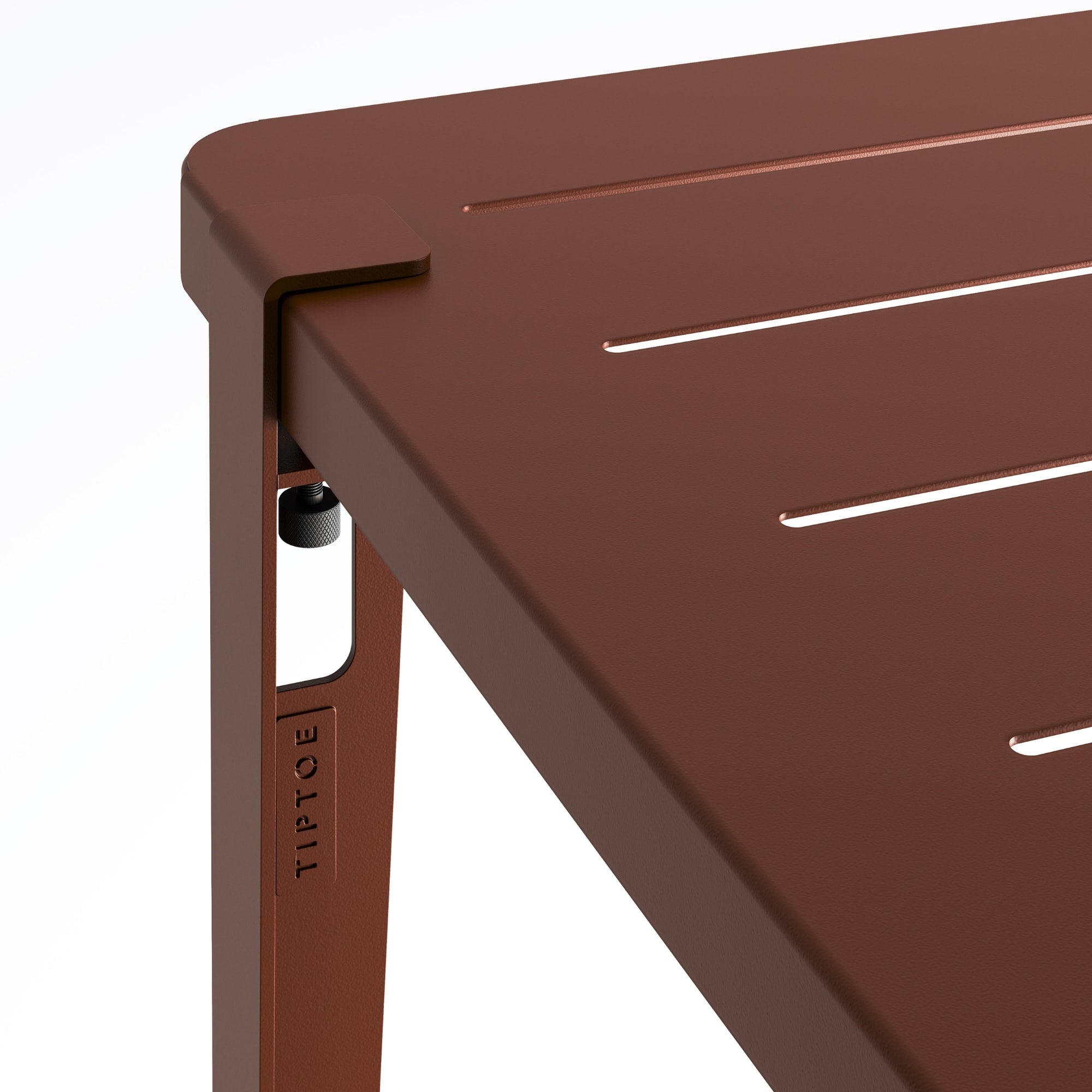 Zoom sur l’angle de la table de jardin Tiptoe en métal rouge brique, montrant le système de fixation du pied et les rainures du plateau.