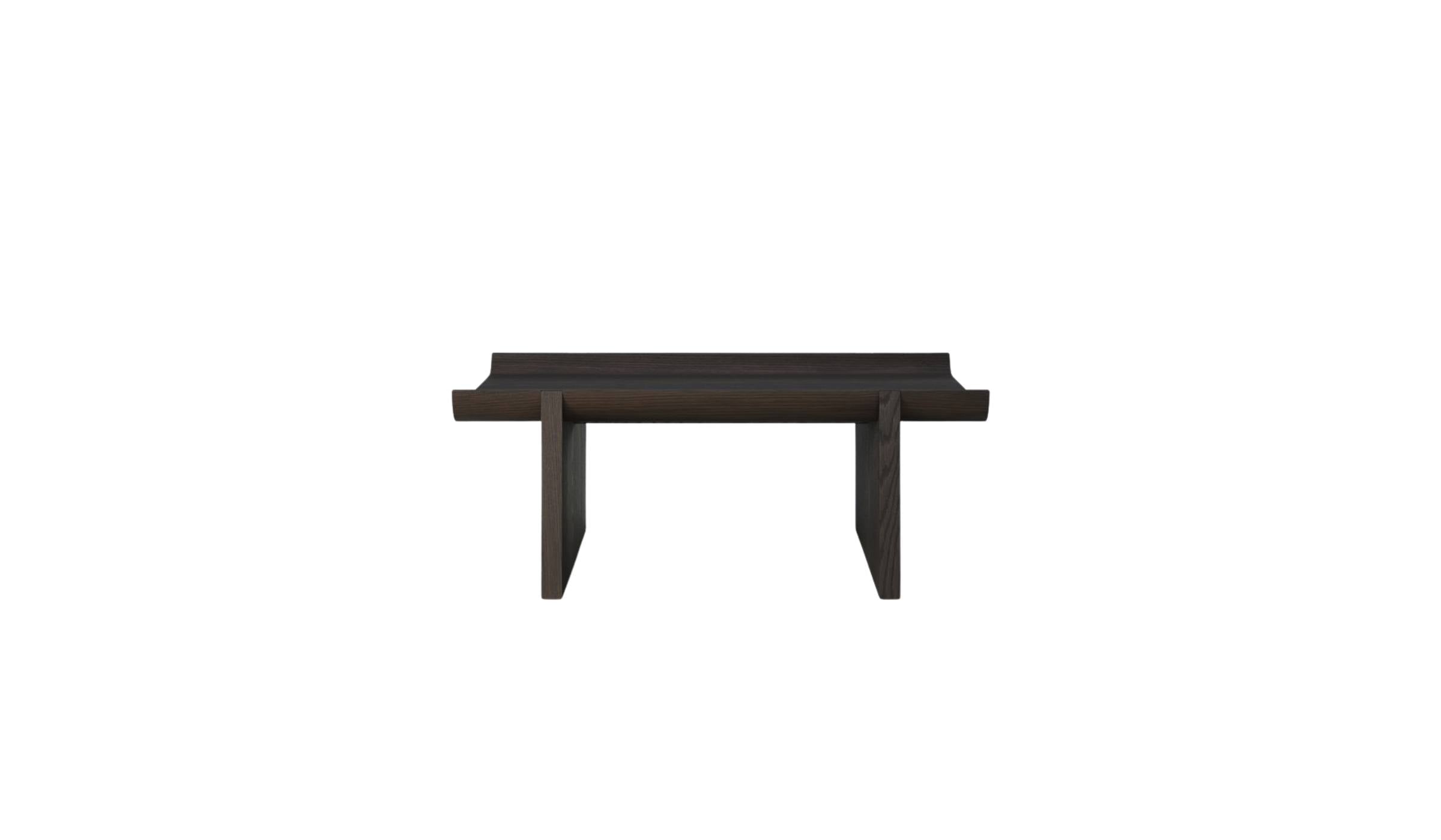 Table basse Rigoles de WeWood en chêne brun, vue de face sur fond blanc, piètement géométrique et plateau incurvé