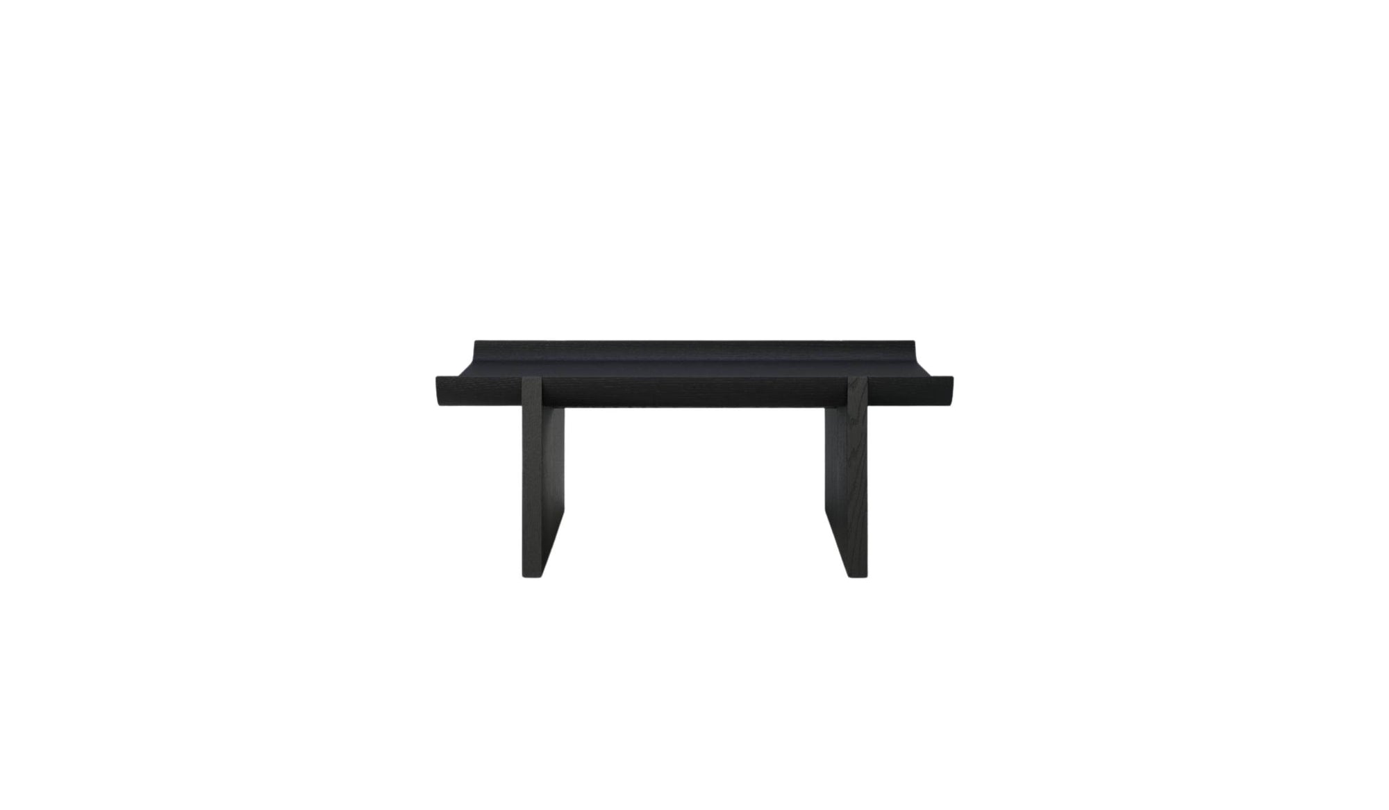 Table basse Rigoles de WeWood en chêne fumé, vue de face sur fond blanc, piètement géométrique et plateau incurvé