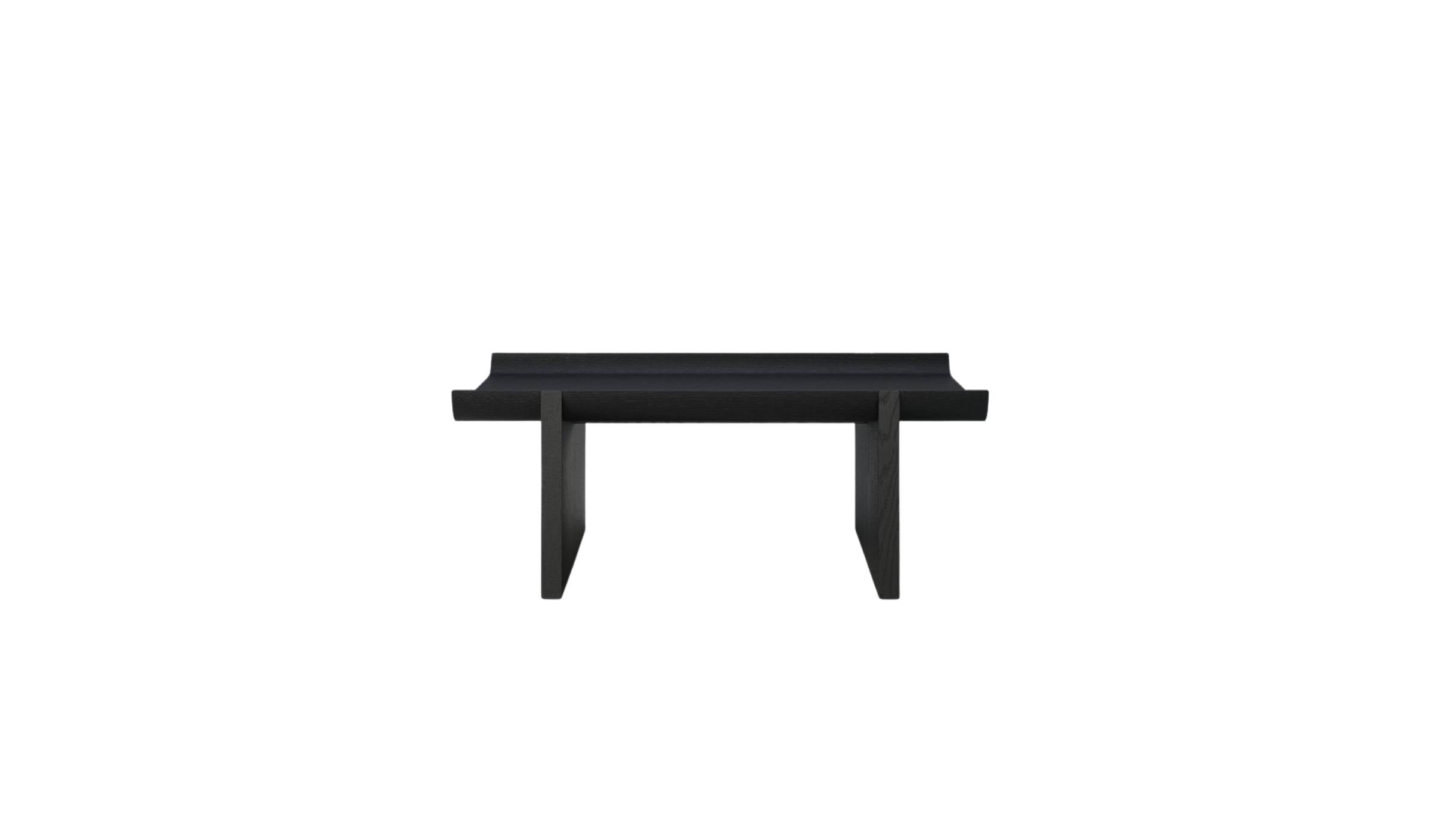 Table basse Rigoles de WeWood en chêne fumé, vue de face sur fond blanc, piètement géométrique et plateau incurvé