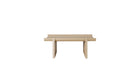 Table basse Rigoles de WeWood en chêne naturel, vue de face sur fond blanc, piètement géométrique et plateau incurvé