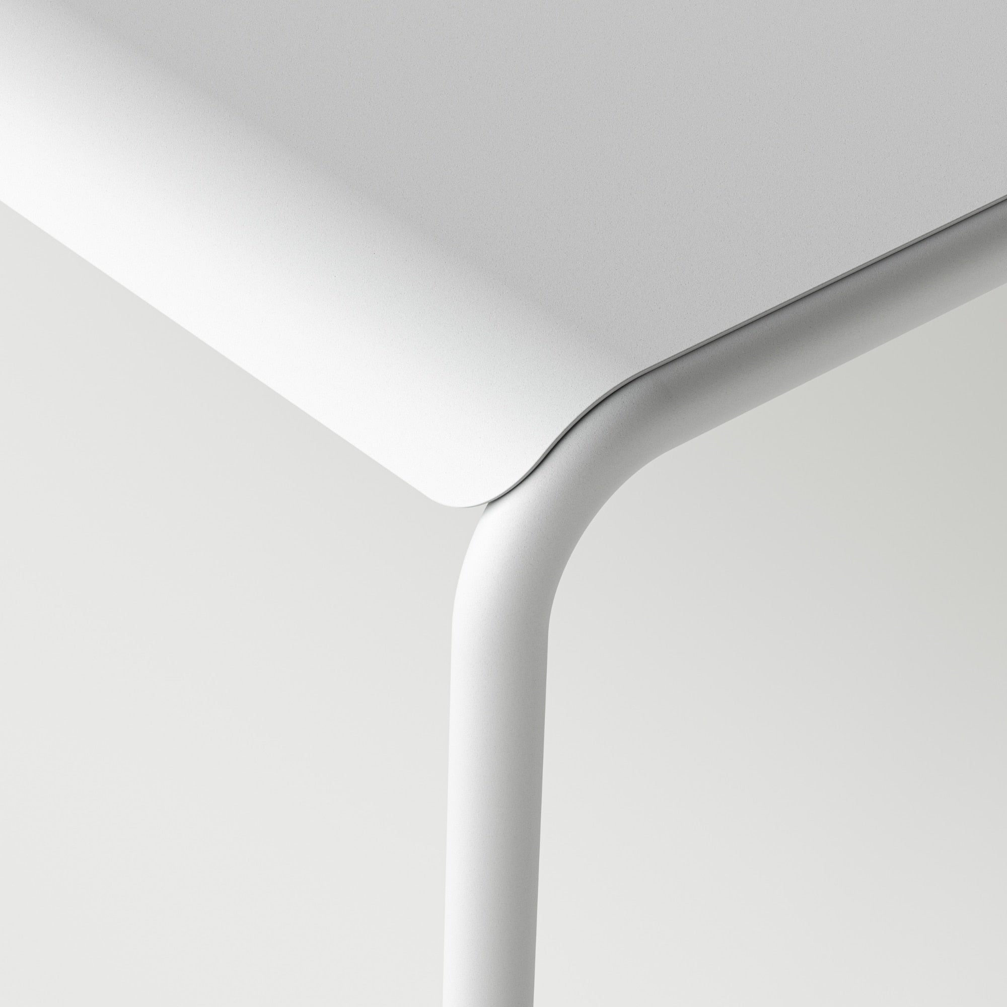 Gros plan sur le coin de la table de jardin, avec des bords arrondis en métal gris craie, mettant en avant le design moderne et épuré du mobilier extérieur Tiptoe.