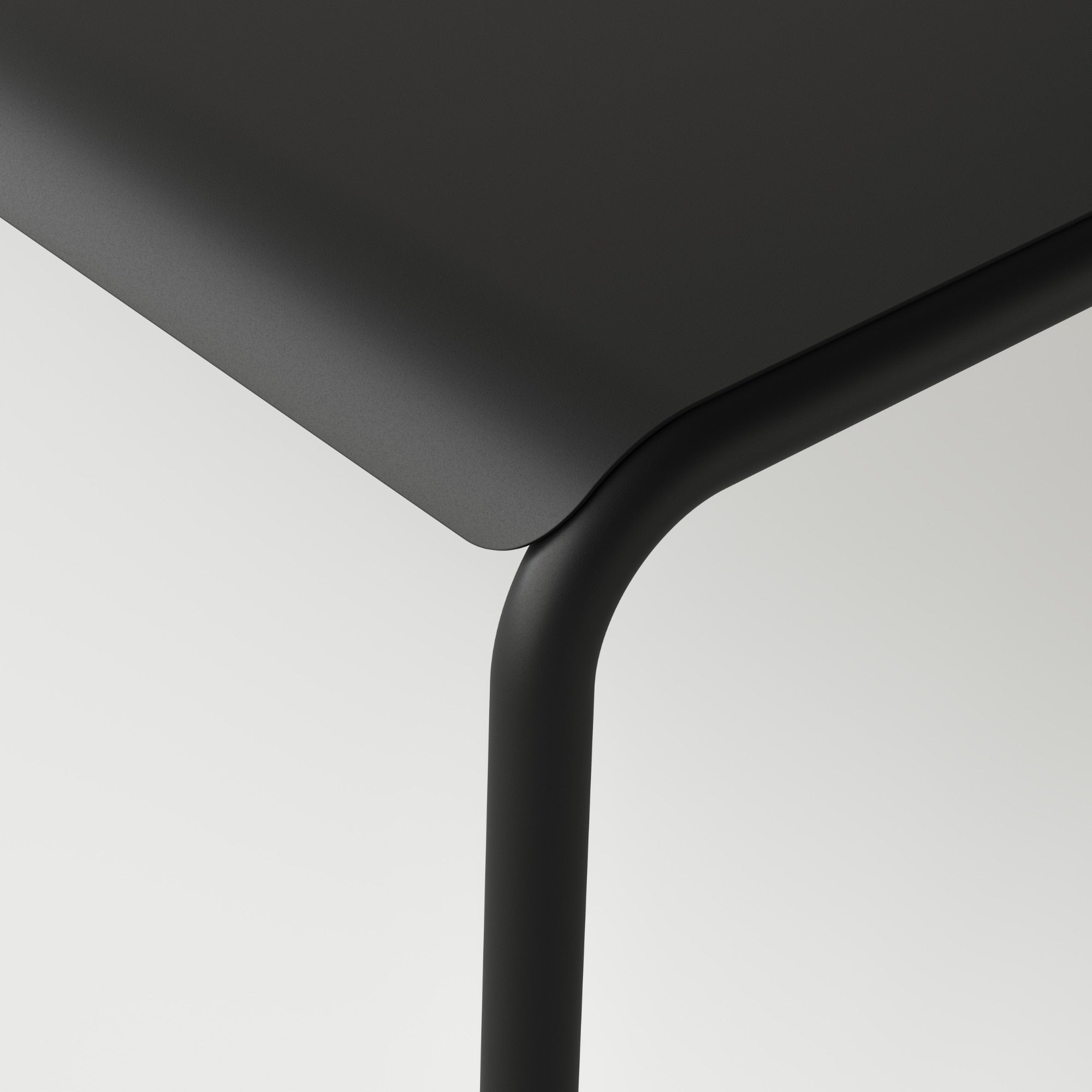 Gros plan sur le coin de la table de jardin, avec des bords arrondis en métal noir graphite, mettant en avant le design moderne et épuré du mobilier extérieur Tiptoe.