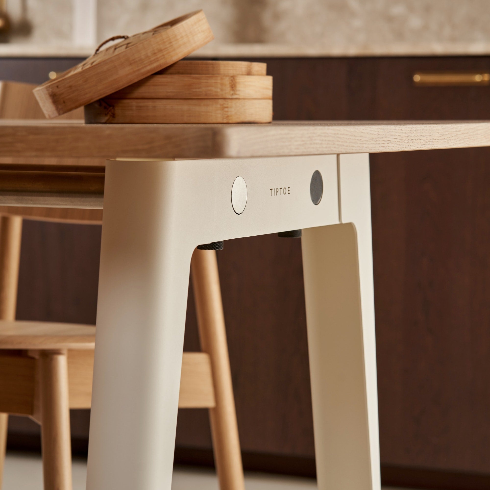 Détail de la table Tiptoe New Modern, modèle en bois éco-certifié et pieds en acier thermolaqué couleur blanc nuage, avec des accessoires en bois sur le dessus.