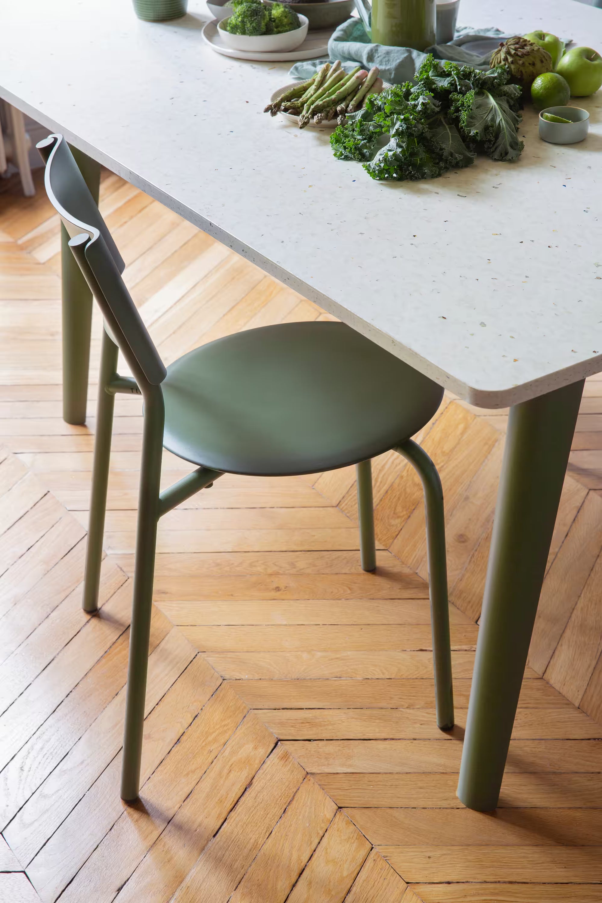 Table en plastique recyclé blanc moucheté et pieds verts, mise en scène avec légumes verts dans un intérieur parqueté