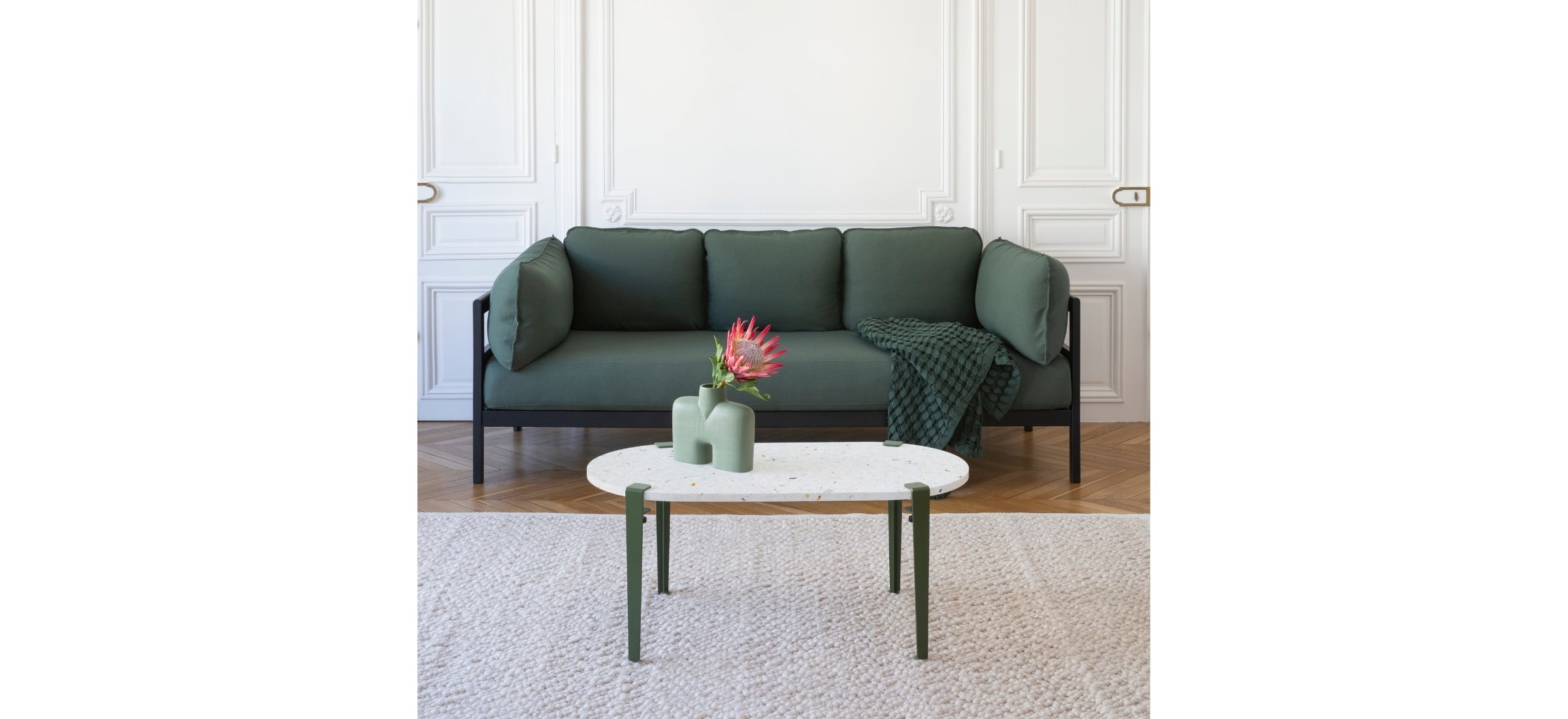 Canapé Easy 3 places en tissu vert forêt, accompagné d’une table basse en terrazzo et d’un vase décoratif, installé sur un tapis texturé dans un intérieur au style haussmannien.