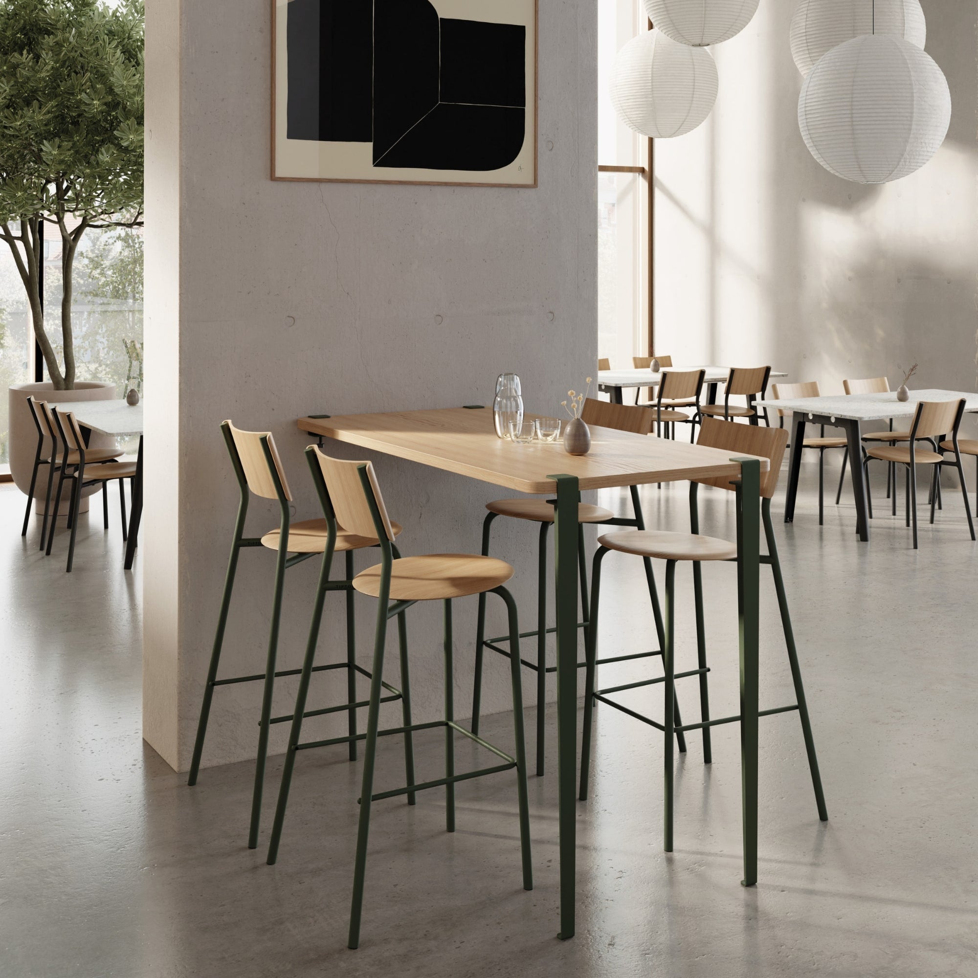 Ensemble de quatre chaises hautes en bois clair avec piètement métallique vert foncé autour d’une table haute rectangulaire en bois dans un espace ouvert de restauration contemporain.