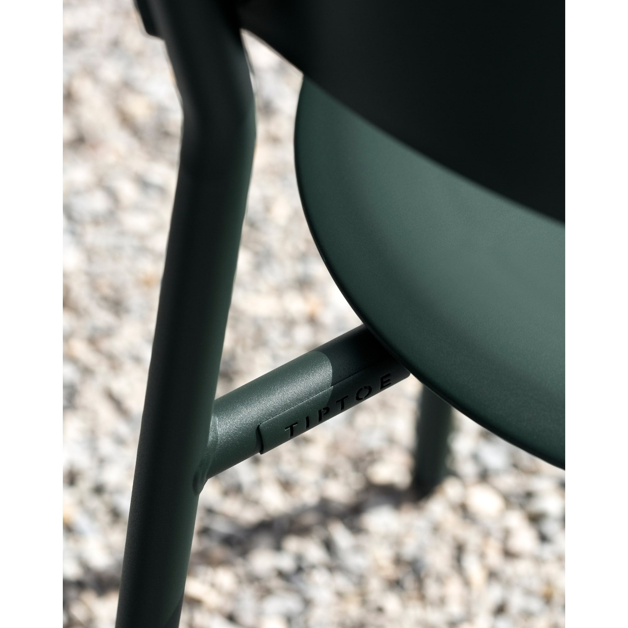 Détail d’une chaise d’extérieur en métal vert avec le logo Tiptoe gravé sur la structure.